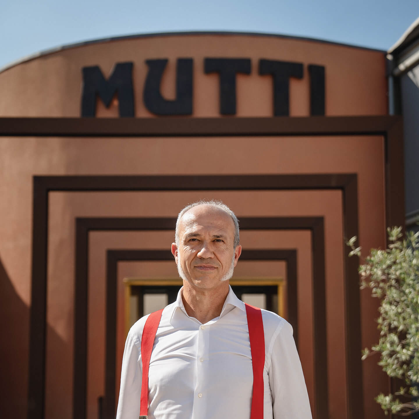 Man in red braces standing before the Mutti company entrance