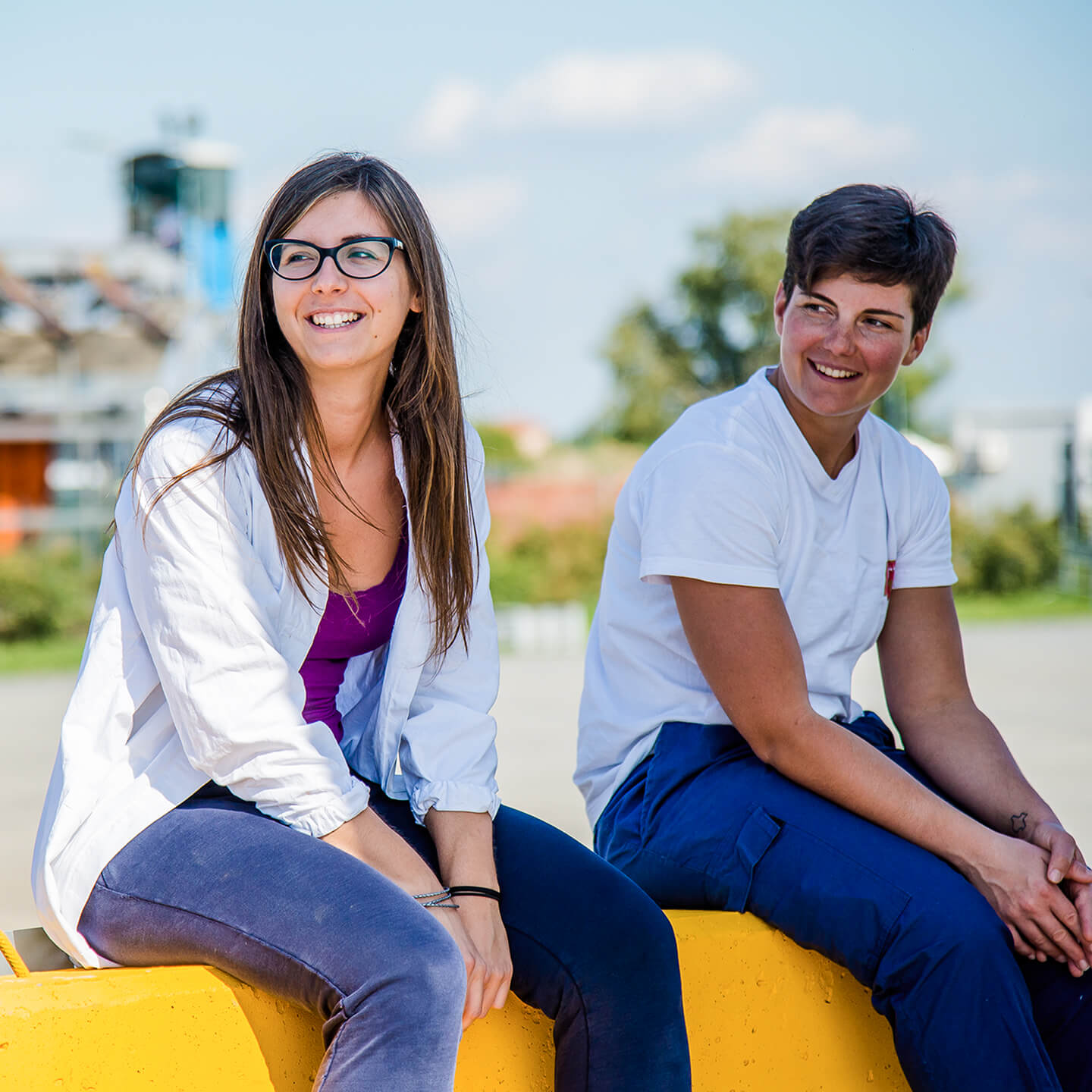 Two Mutti employees smiling outdoors on yellow silos