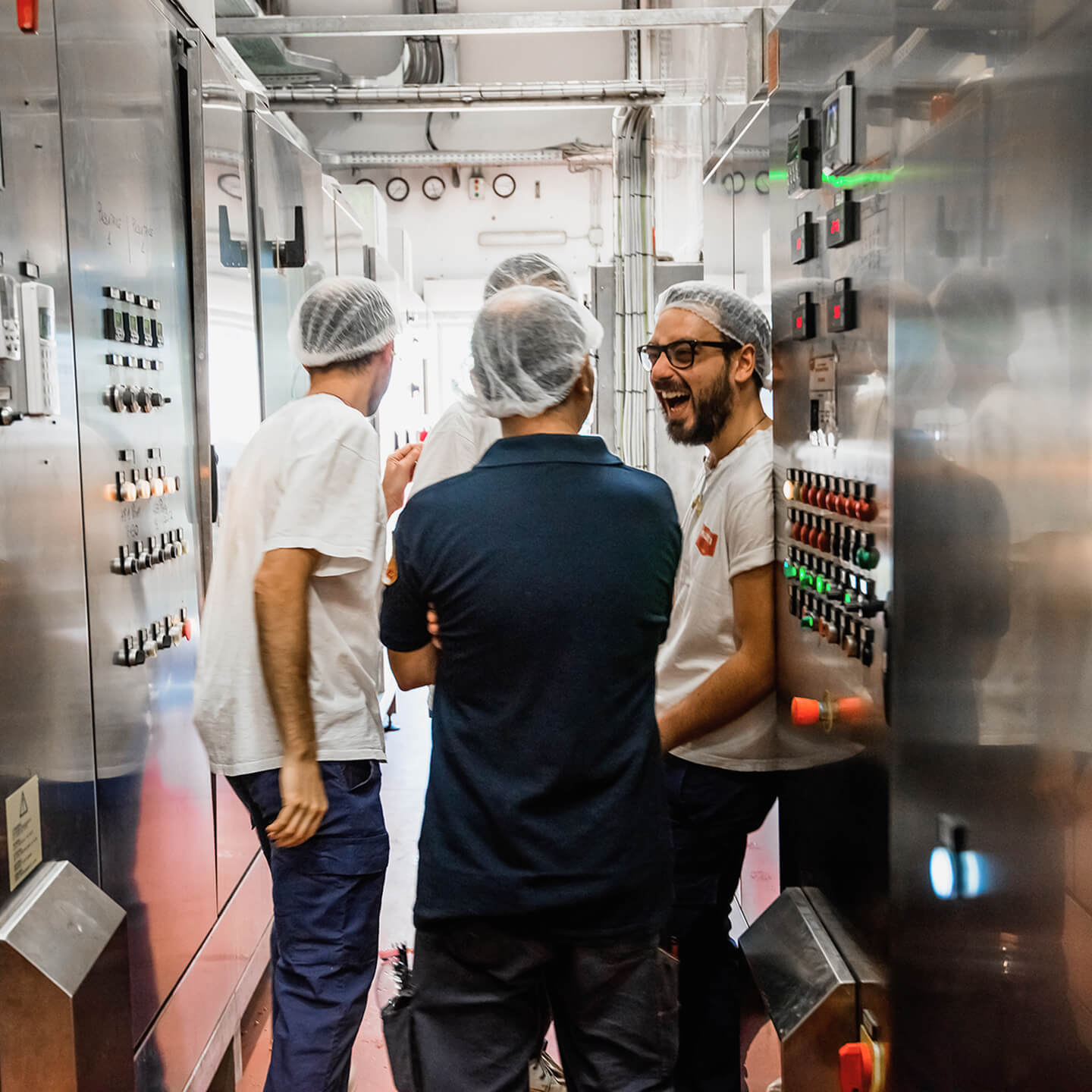 Mutti factory workers in hairnets chatting in a control room