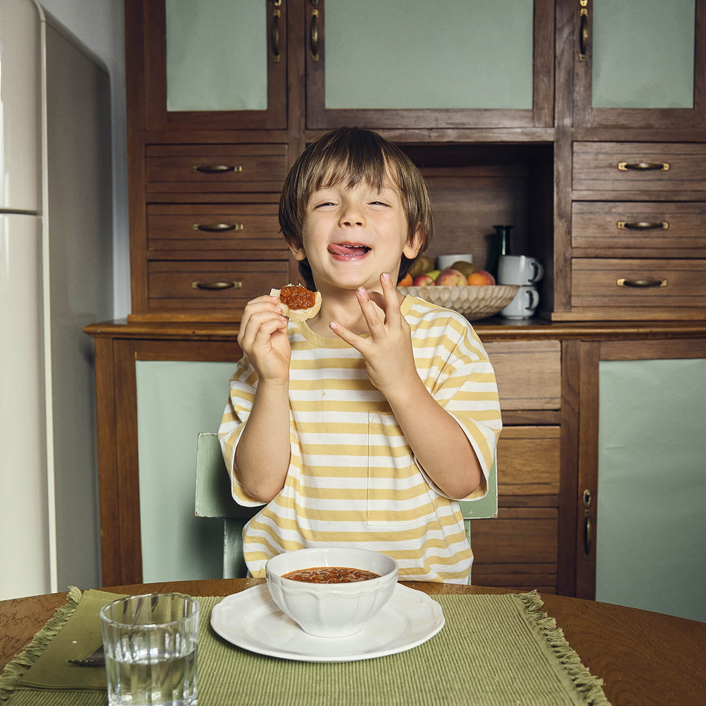 Boy enjoying bread with tomato spread at the kitchen table