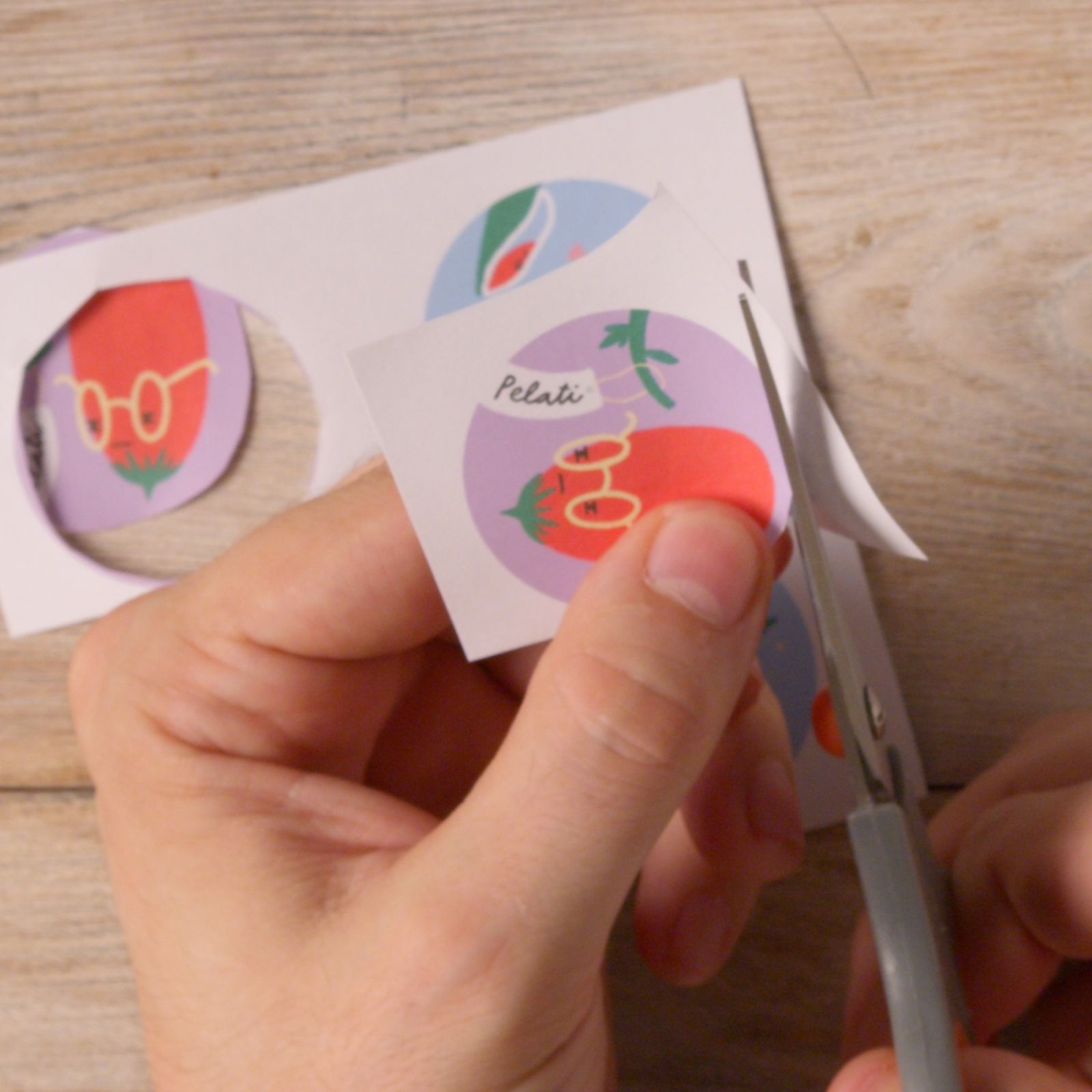 Hands cutting out printed tomato illustration circles with scissors