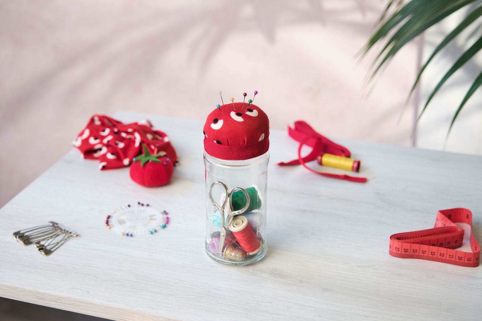 Mutti jar upcycled into a pincushion surrounded by sewing supplies
