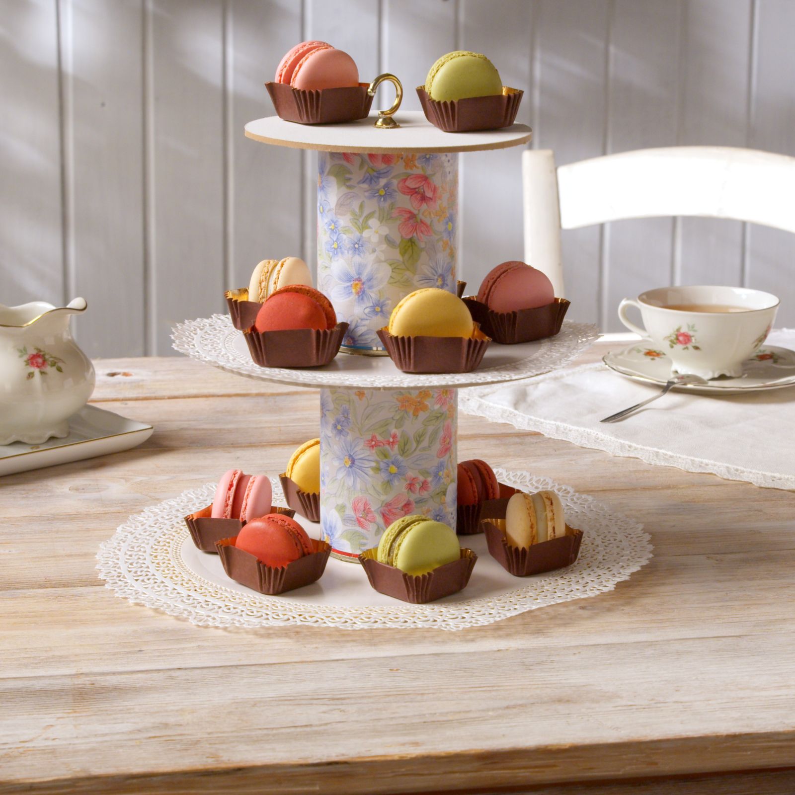 Two-tier dessert stand with macarons and pastries at a tea table