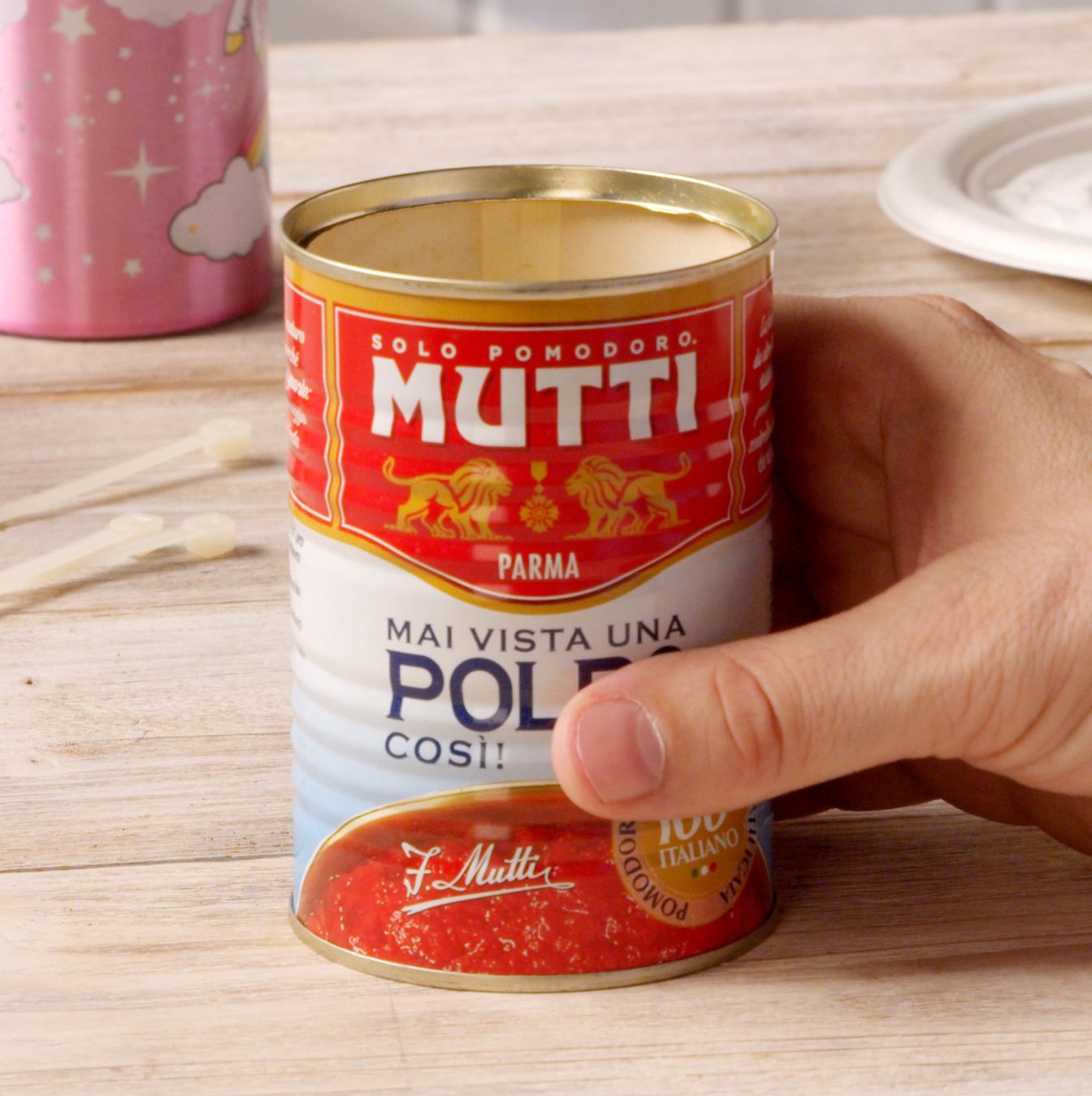 Hand holding an opened Mutti Polpa can ready for upcycling