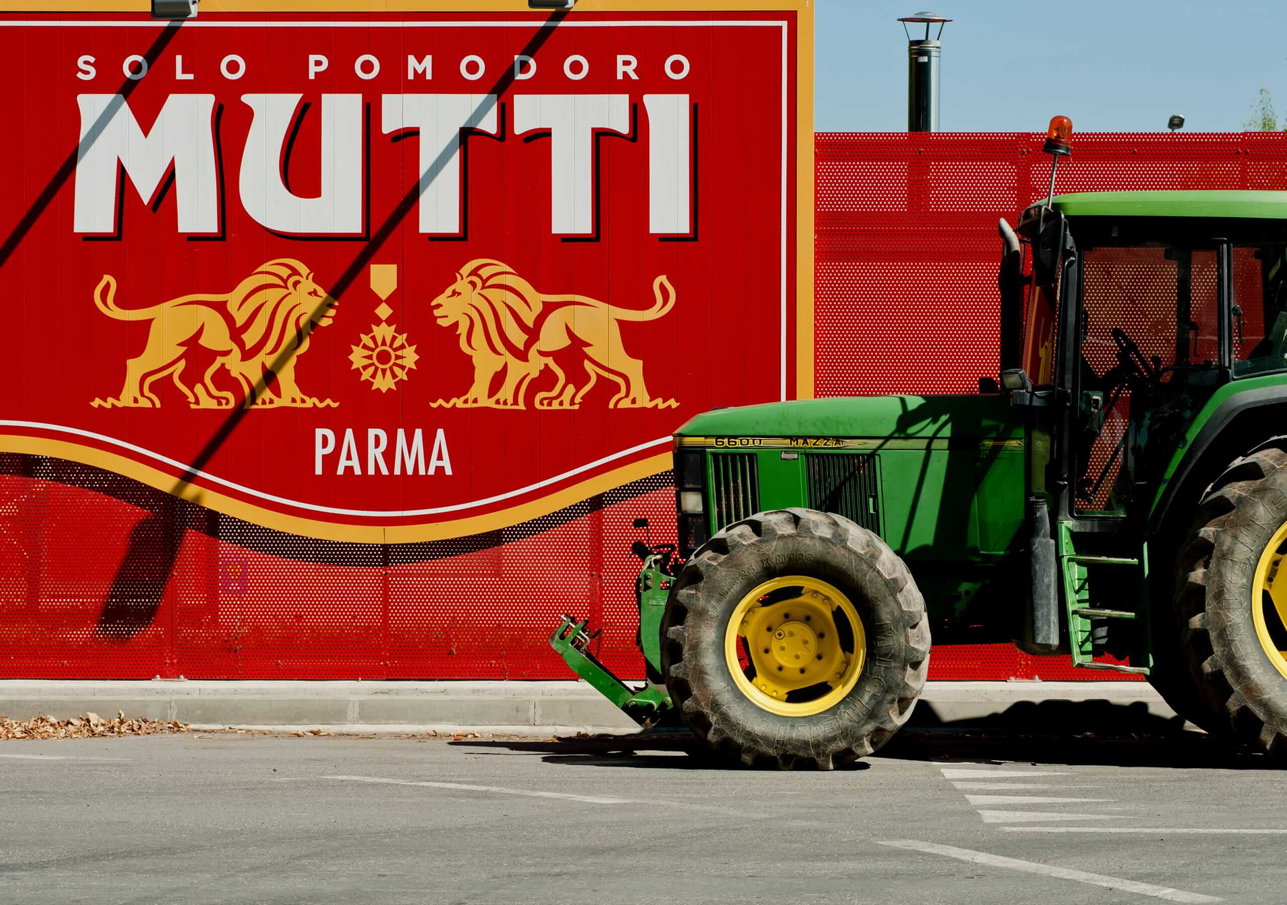 Green tractor parked in front of a large Mutti Parma billboard