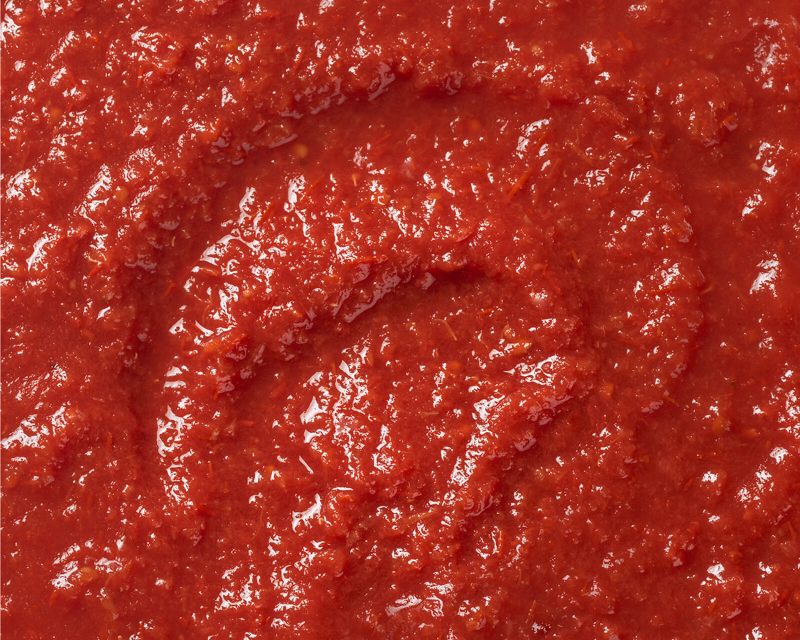 Close-up swirl of smooth red pizza sauce