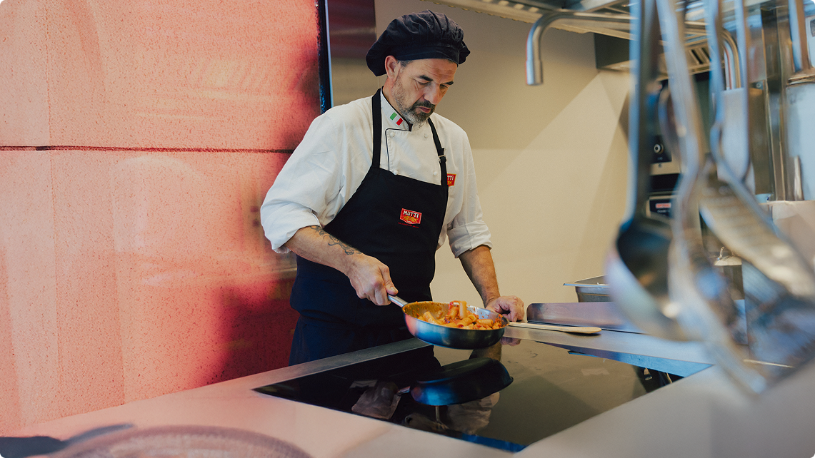 Chef in a Mutti apron plating food in a professional kitchen