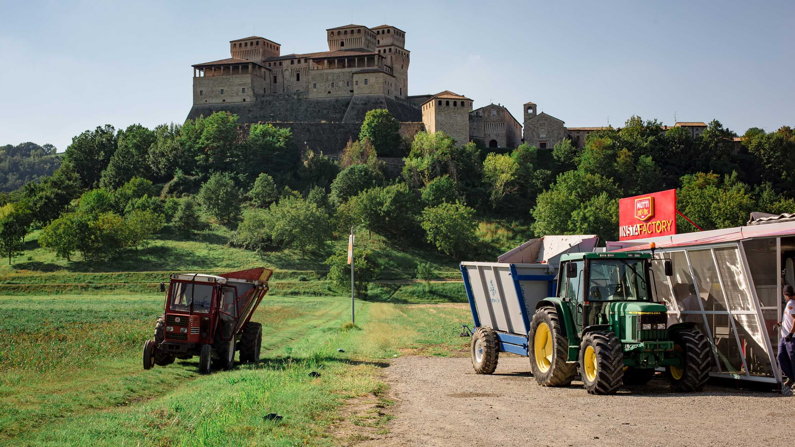 Tractors and Instafactory trailer in a field below a hilltop castle