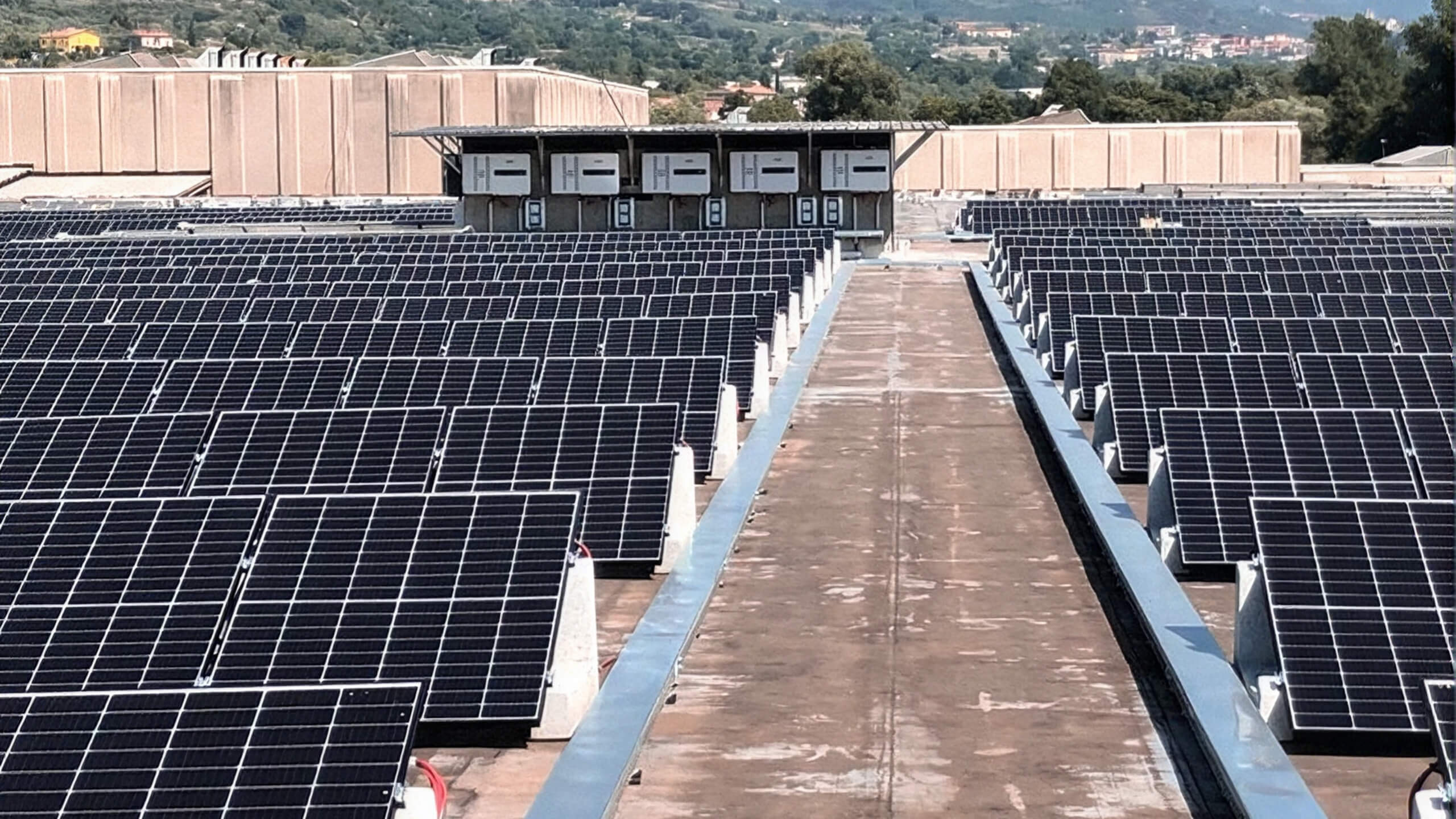 Rows of solar panels on a factory rooftop with a central walkway