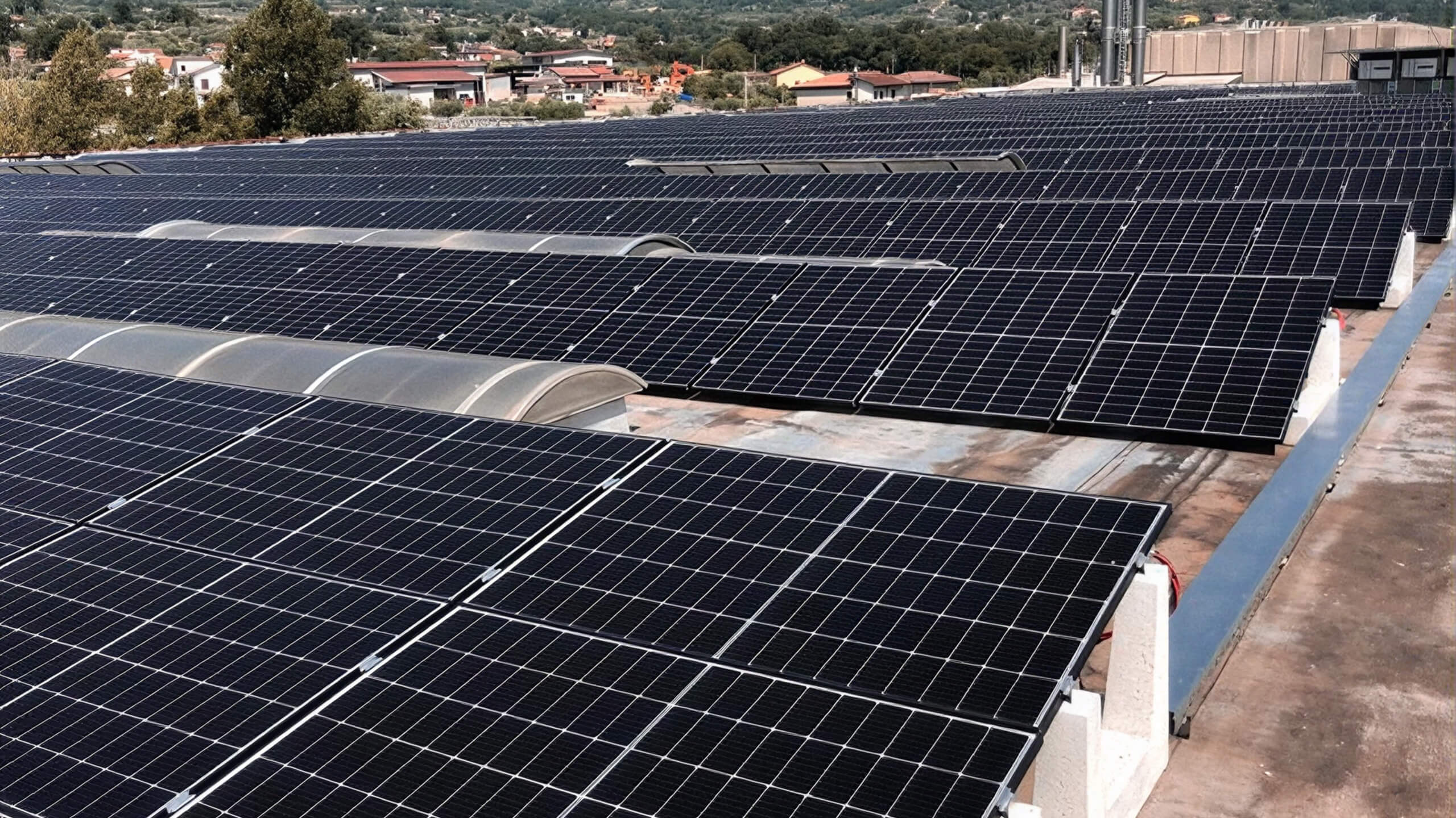 Solar panel array on a factory roof overlooking nearby houses