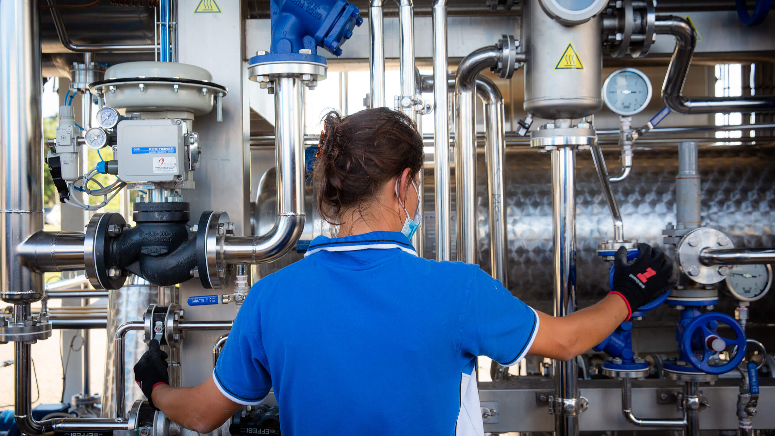 Mutti worker adjusting valves on stainless steel factory pipework