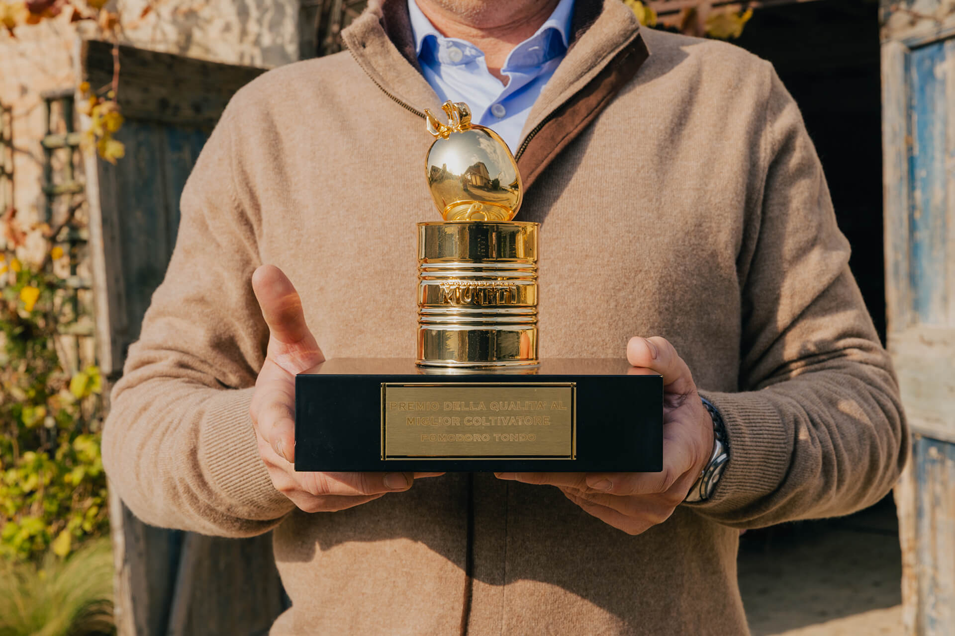 Close-up of hands holding the golden Pomodorino d'Oro trophy