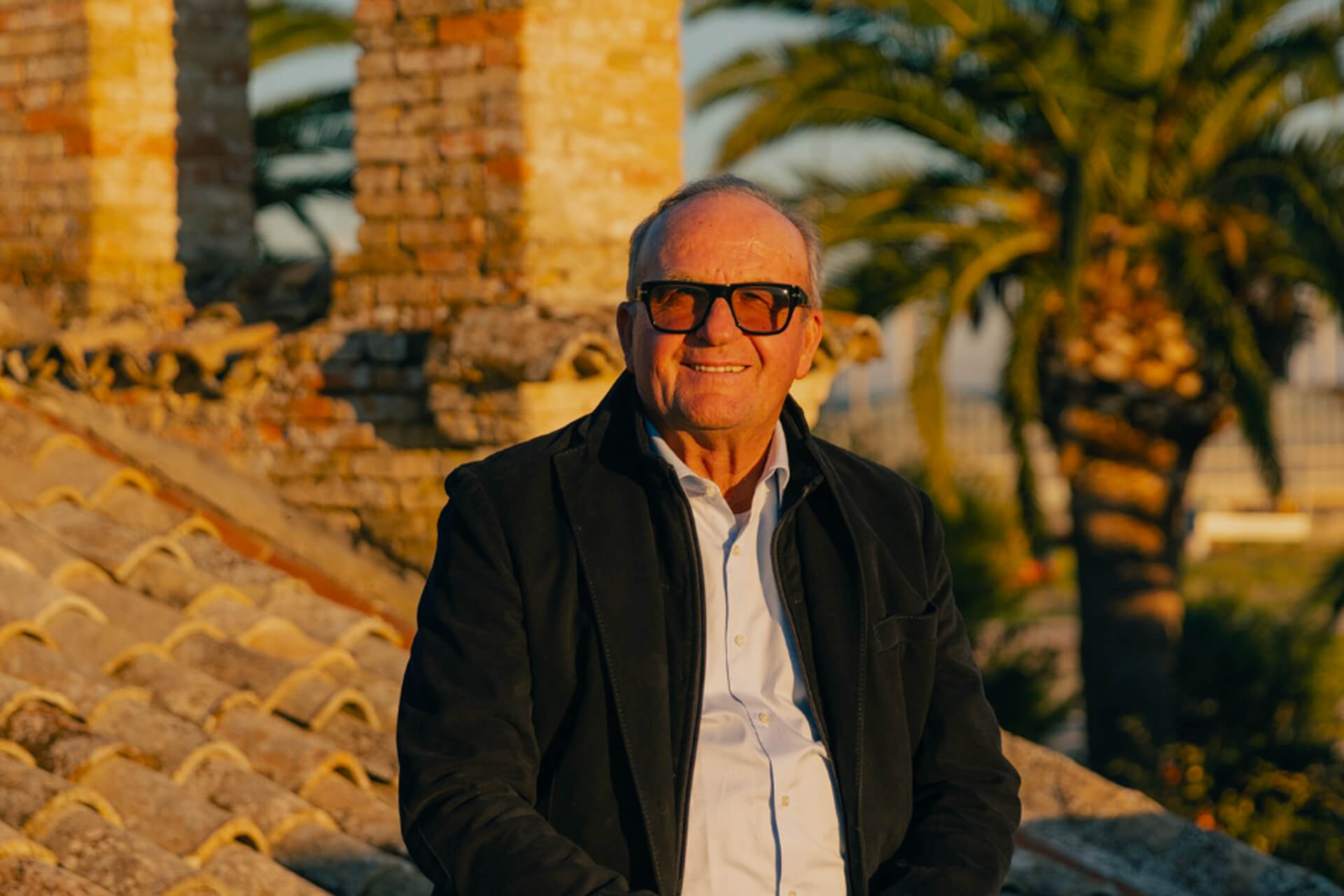 Man in sunglasses smiling on a rooftop at sunset