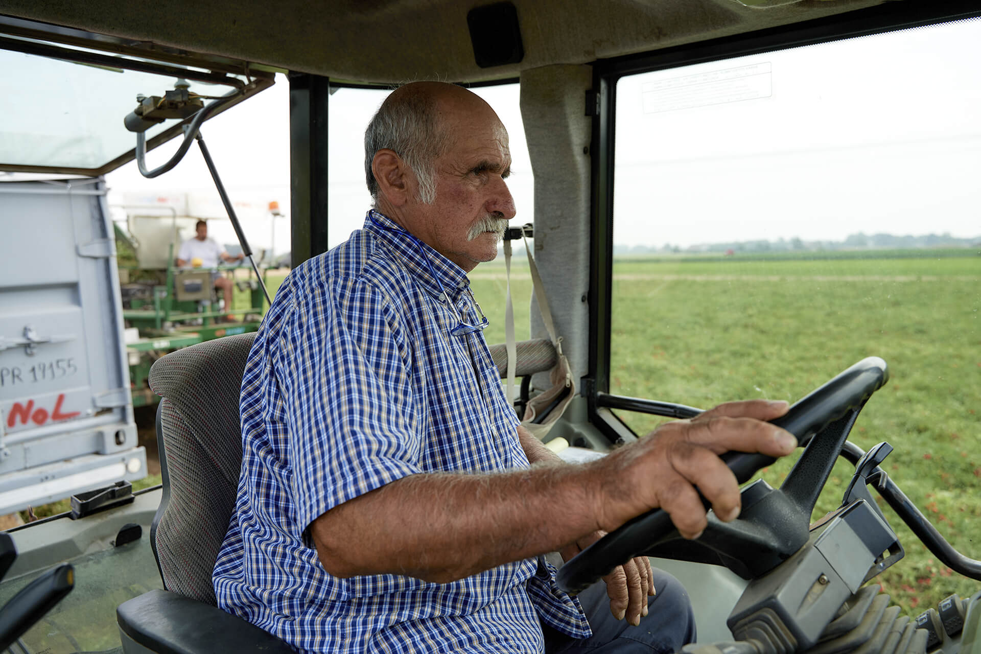 Farmer driving a tractor across an open green field