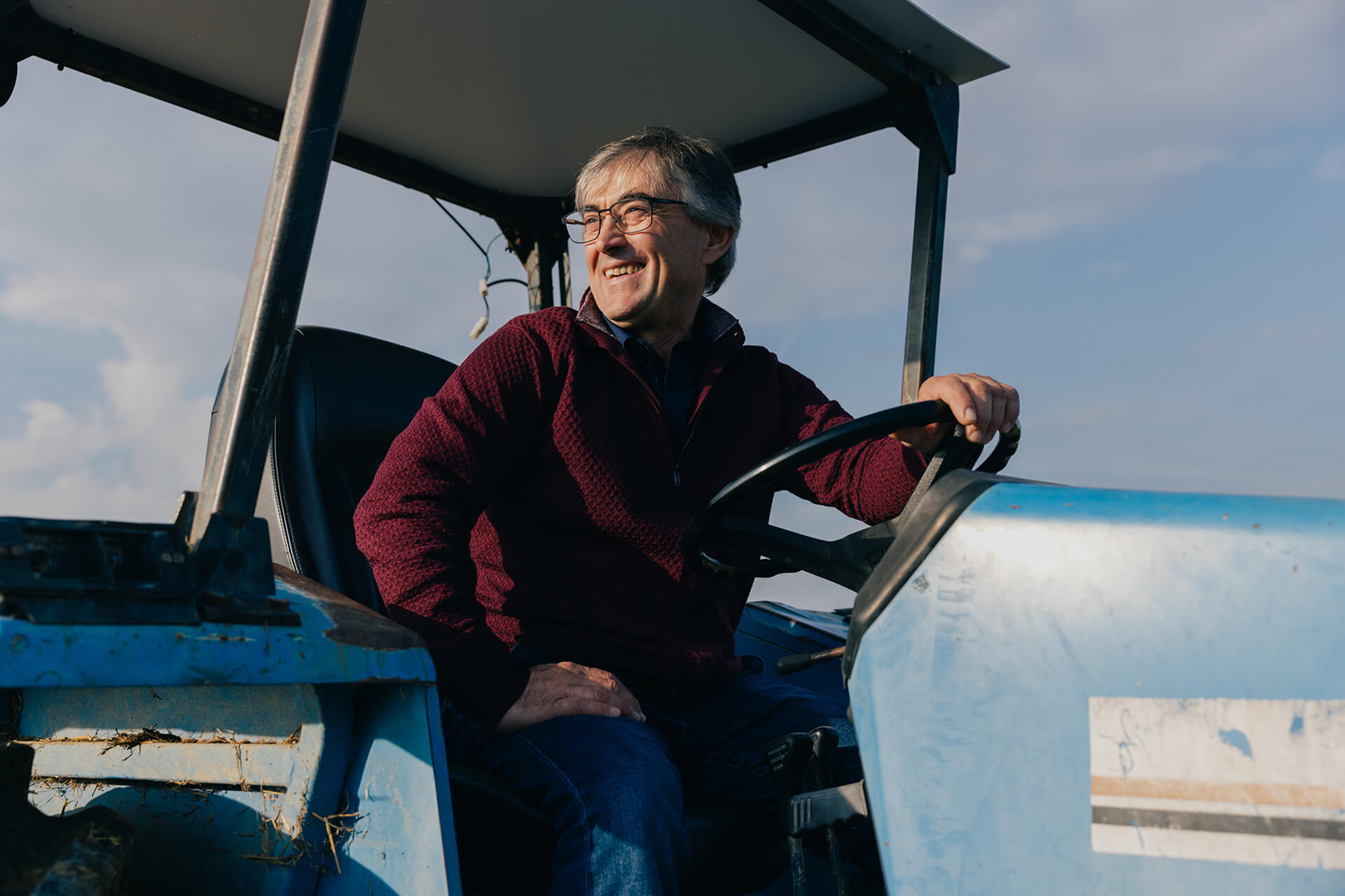 Mutti farmer smiling while driving a tractor in a field