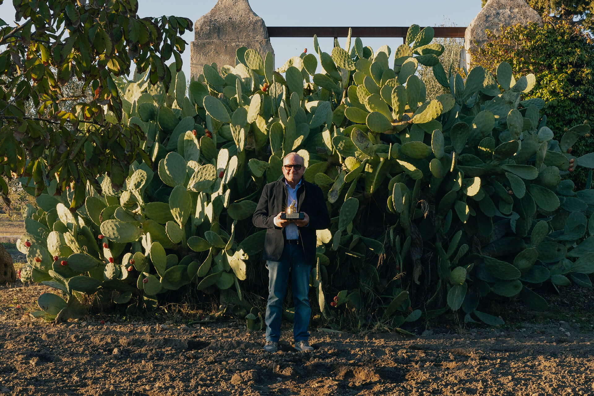 Mutti farmer holding an award among tall prickly pear cacti