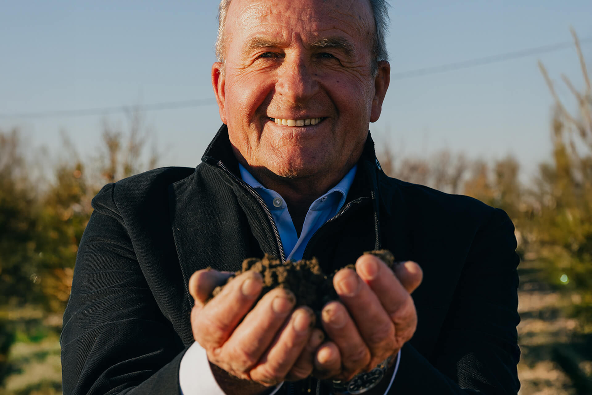 Mutti farmer holding a handful of soil in an orchard