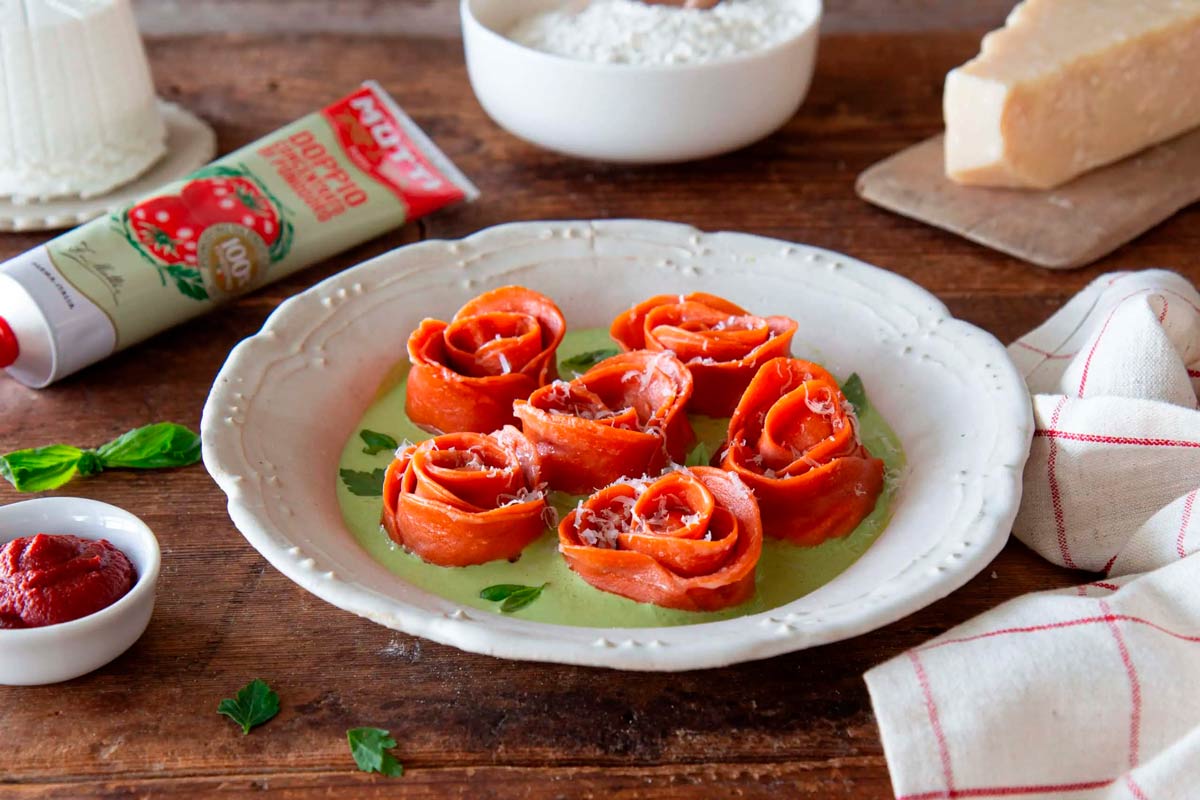 Tomato rose-shaped pasta parcels on a plate with parmesan and basil