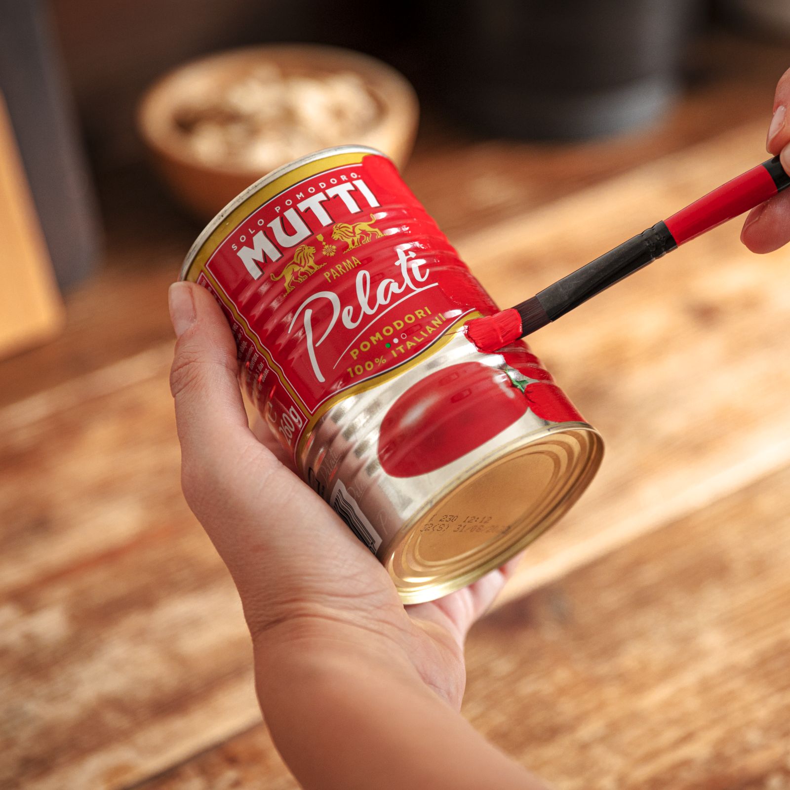 Hand painting a Mutti Pelati can red with a paintbrush