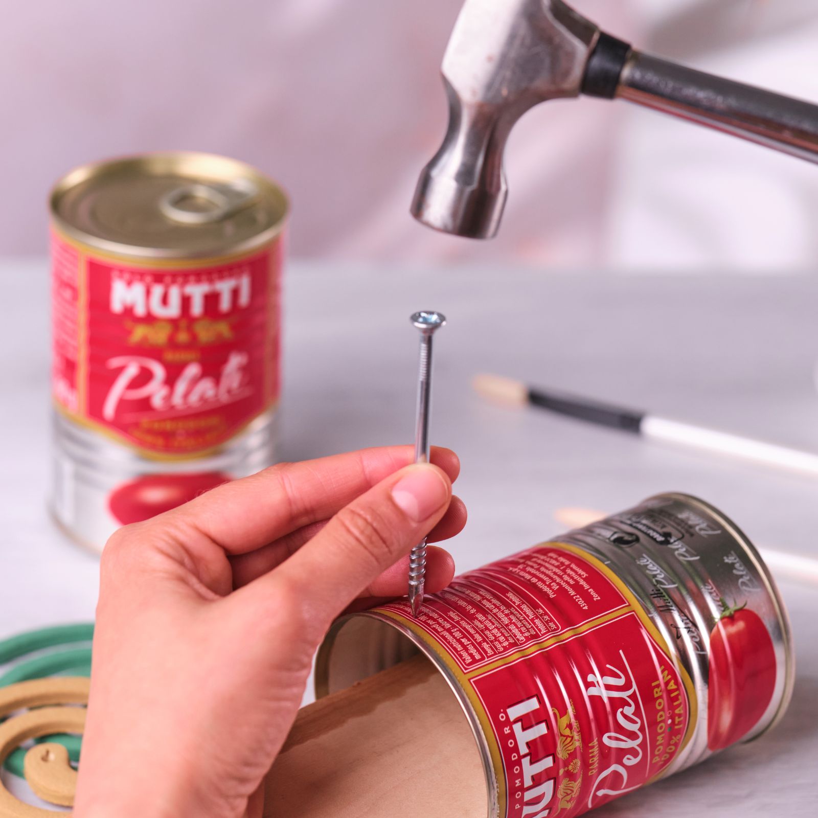 Hammering a nail into a Mutti Pelati can