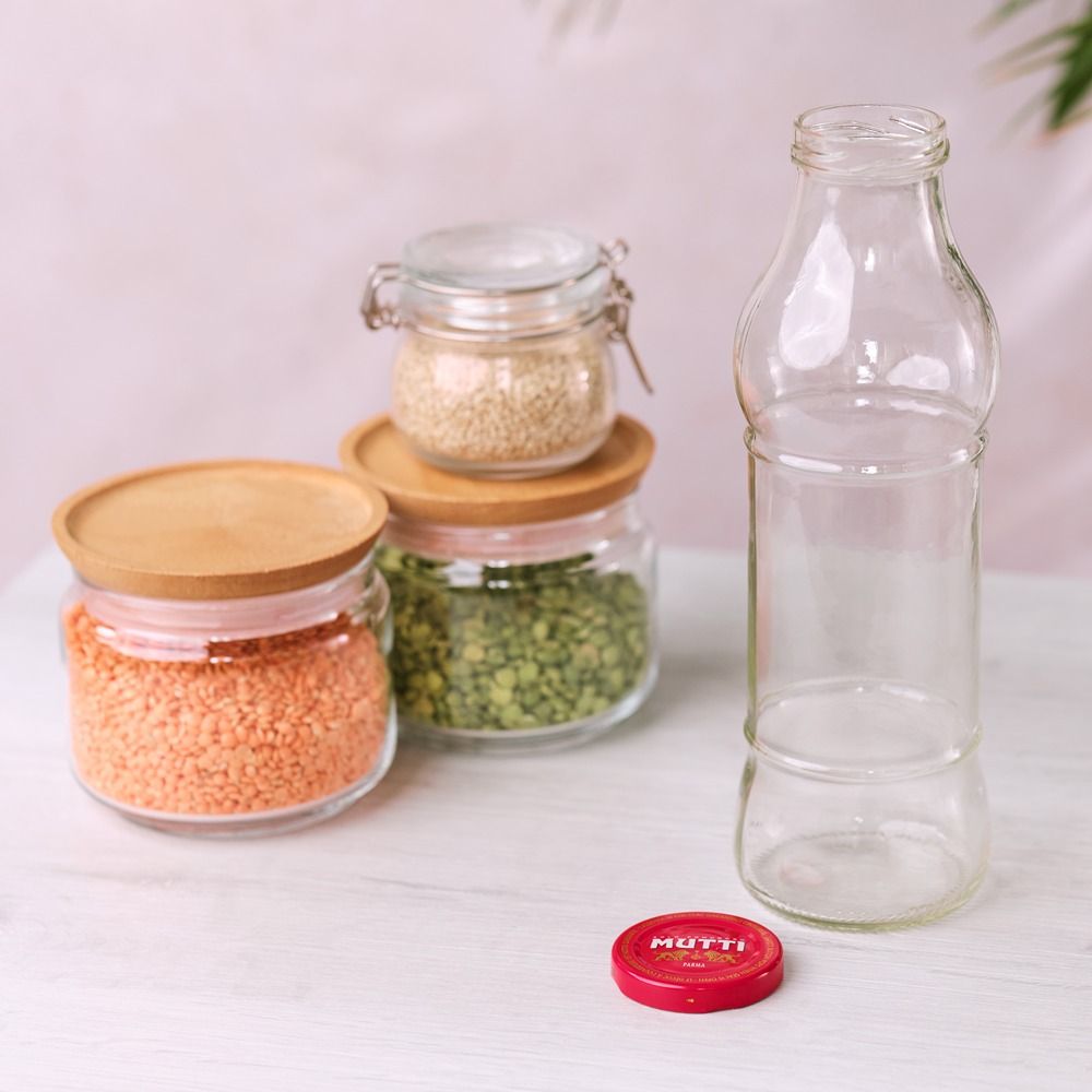 Empty glass bottle next to jars of dried pulses