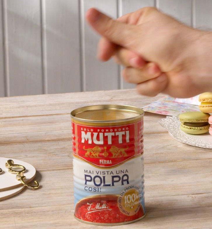 Mutti Polpa can on a table with pastel macarons nearby