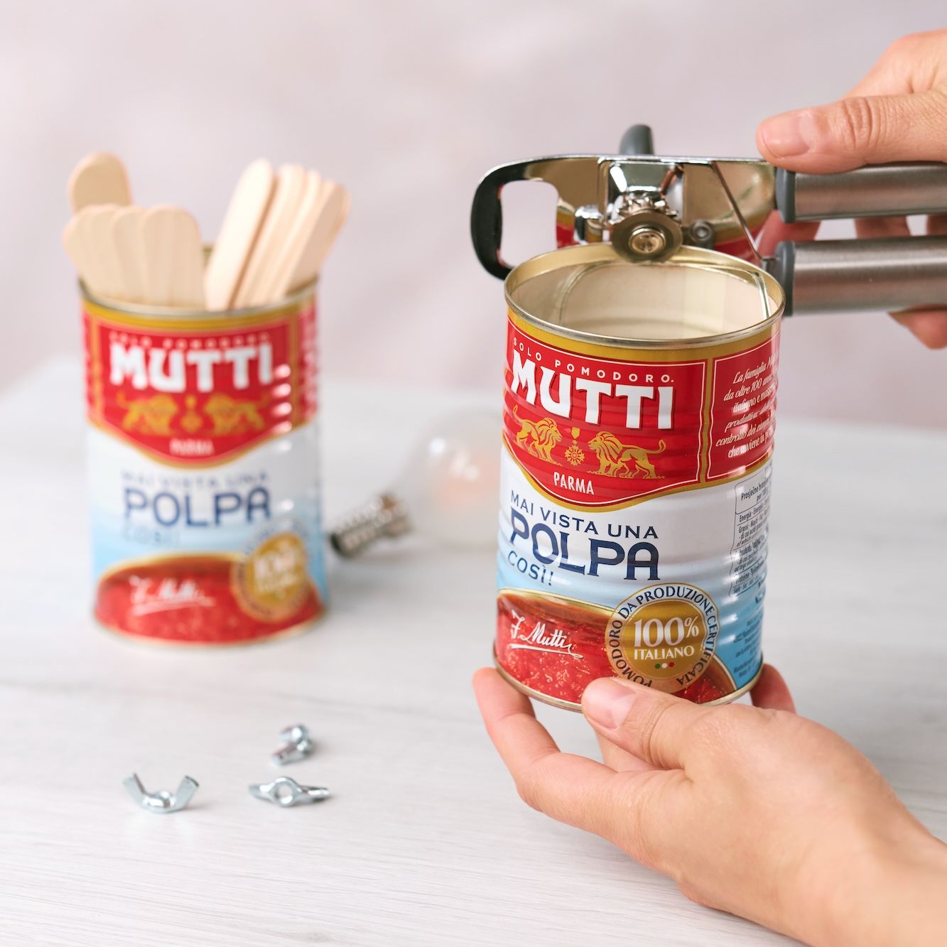Hands opening a Mutti Polpa can with a can opener