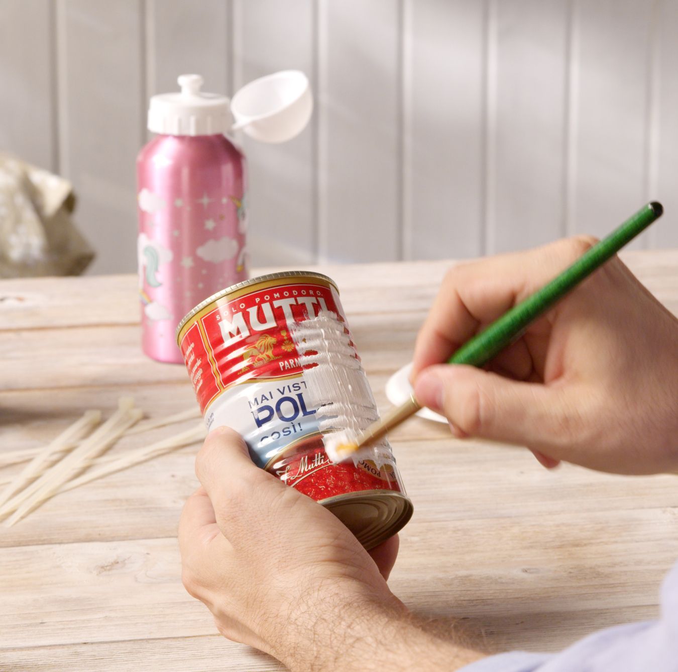 Hands painting a Mutti Polpa can white with a sponge brush