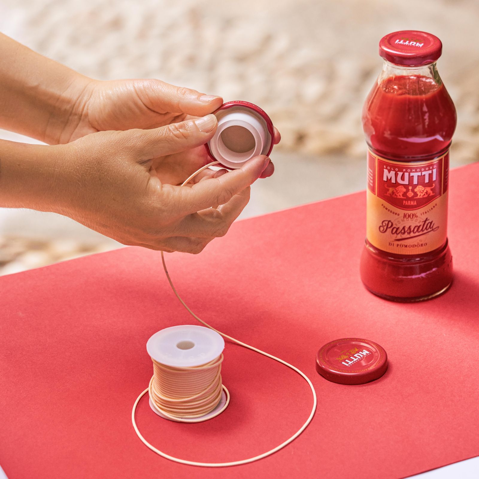 Hands attaching a string spool to the inside of a bottle cap