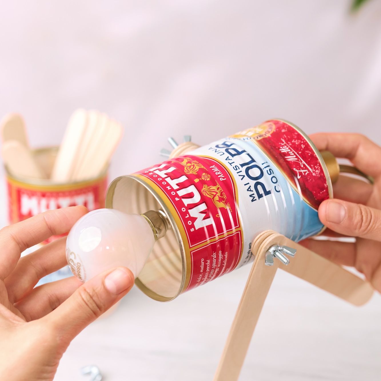 Inserting a light bulb into the lamp holder on a Mutti can