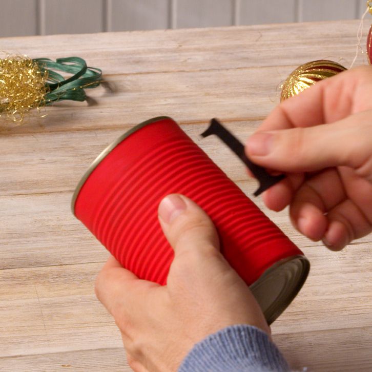 Hands attaching an adhesive number to a red-painted advent calendar can