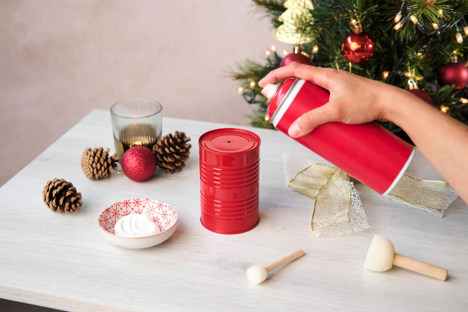 Spray-painting an empty tomato tin red for a Christmas wreath