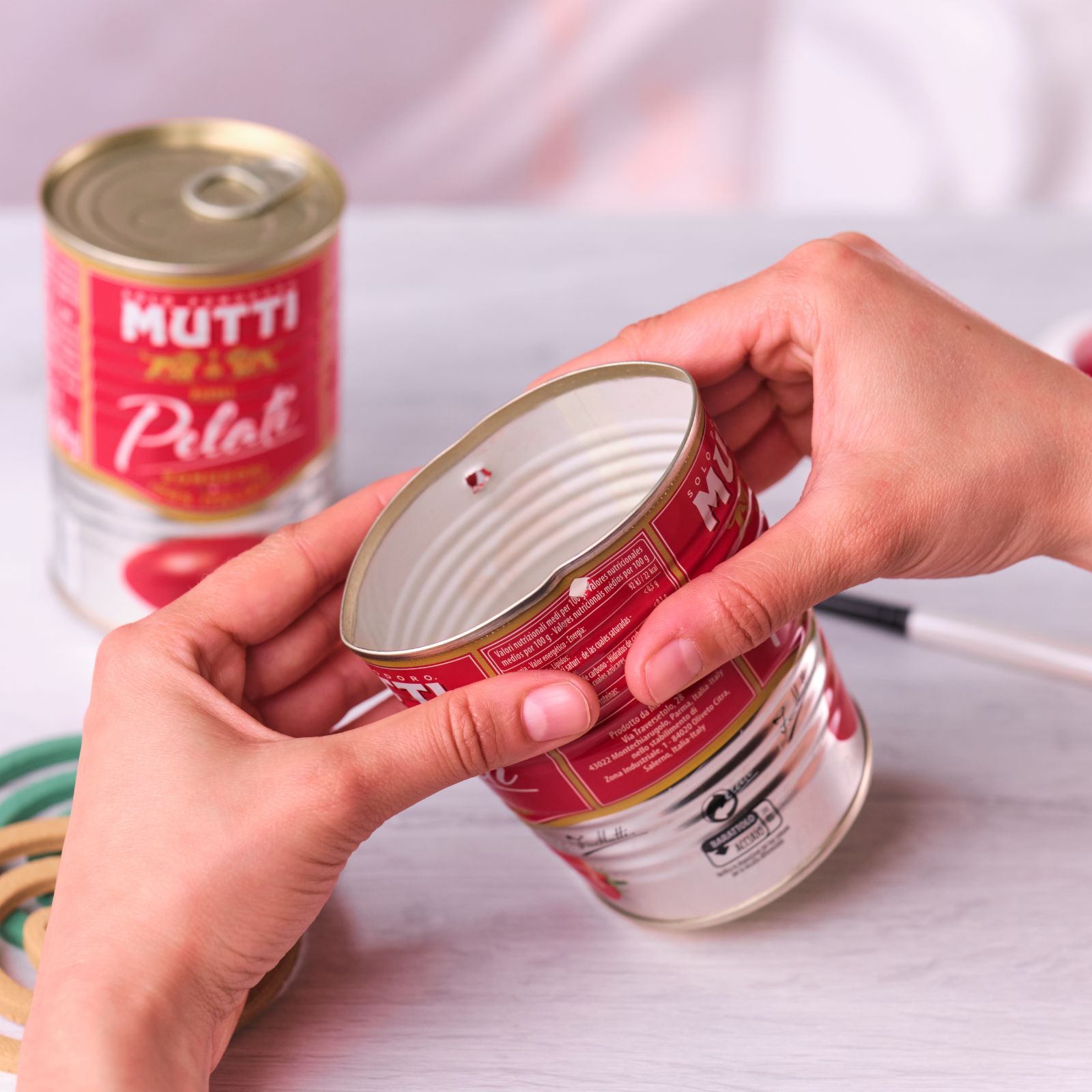 Hands removing the bottom of a Mutti Pelati can