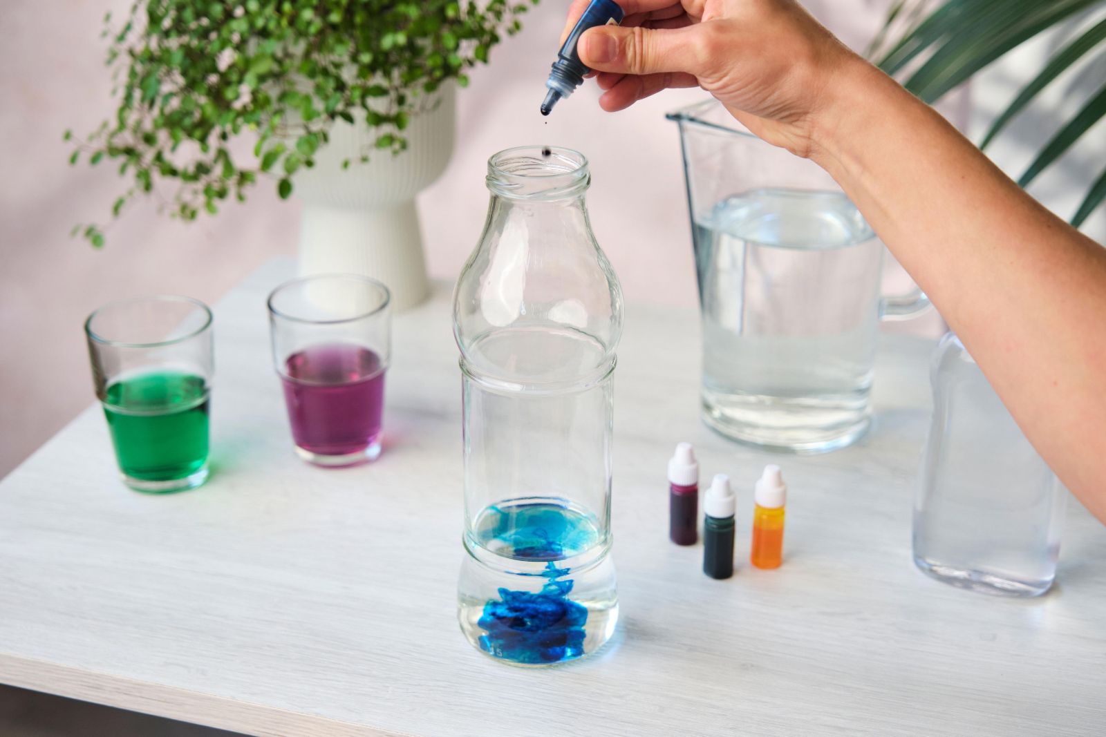 Hand adding a drop of food colouring into a water-filled bottle