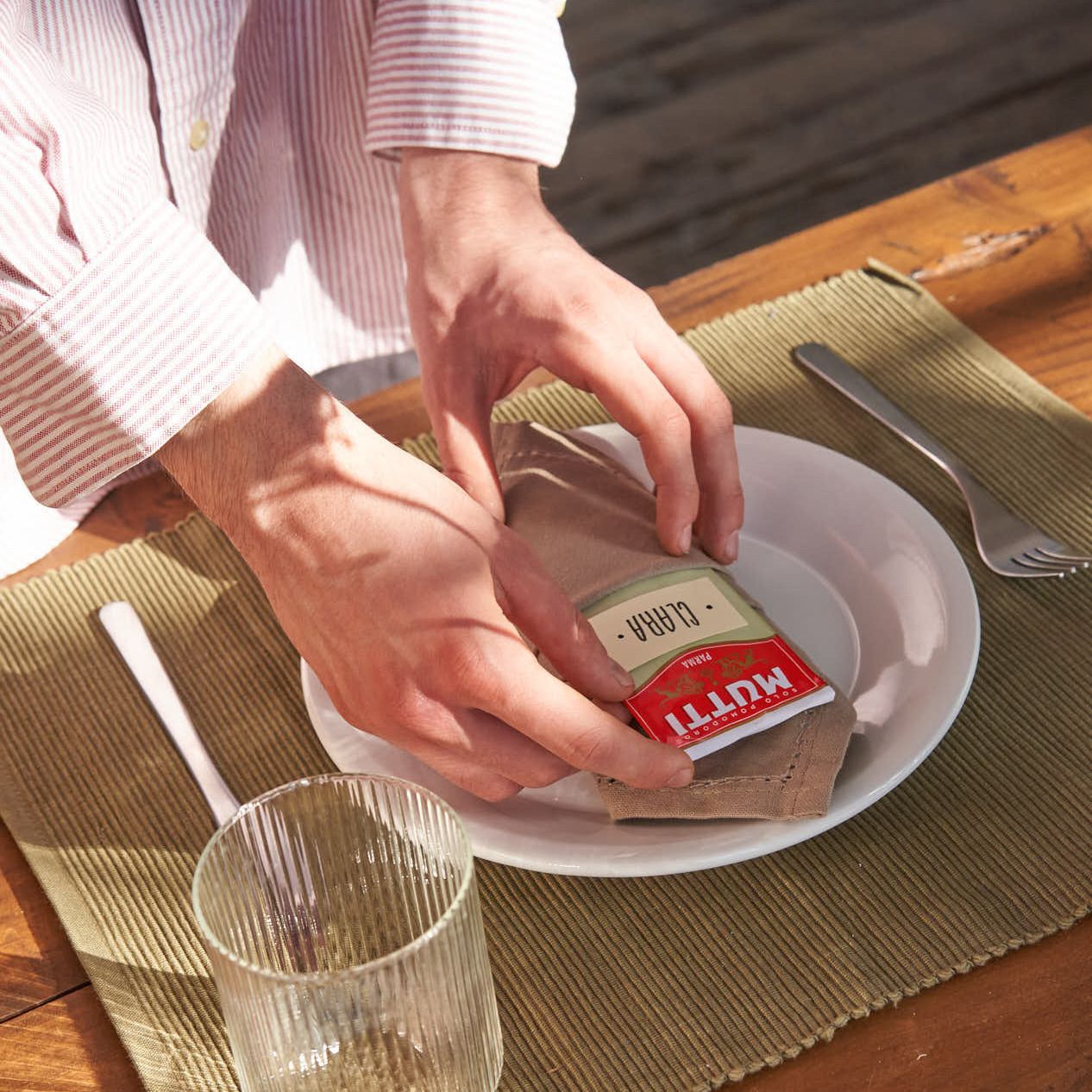 Hands wrapping paper around a small Mutti tin as a place card