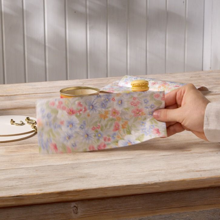 Hand wrapping a floral fabric strip around a tin can