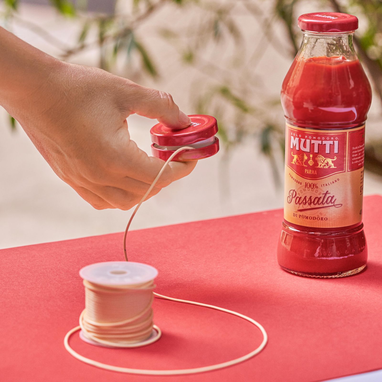 Hand holding a homemade yo-yo made from two Mutti bottle caps