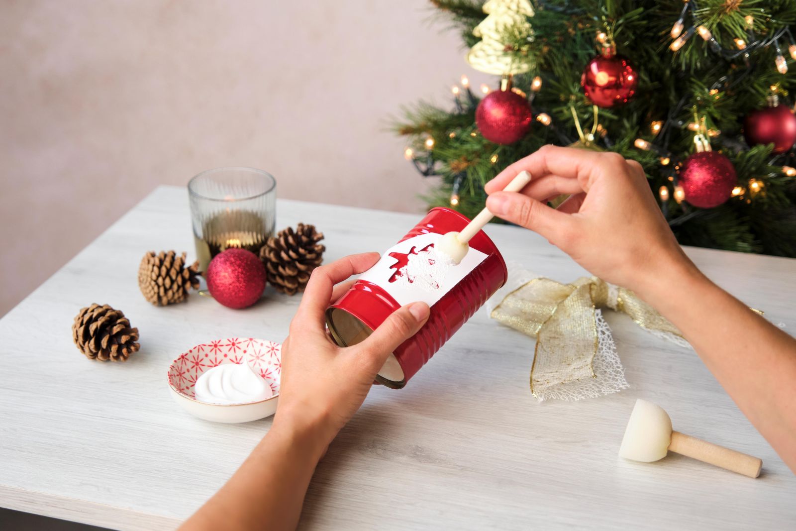 Painting a white reindeer design onto a red tomato tin