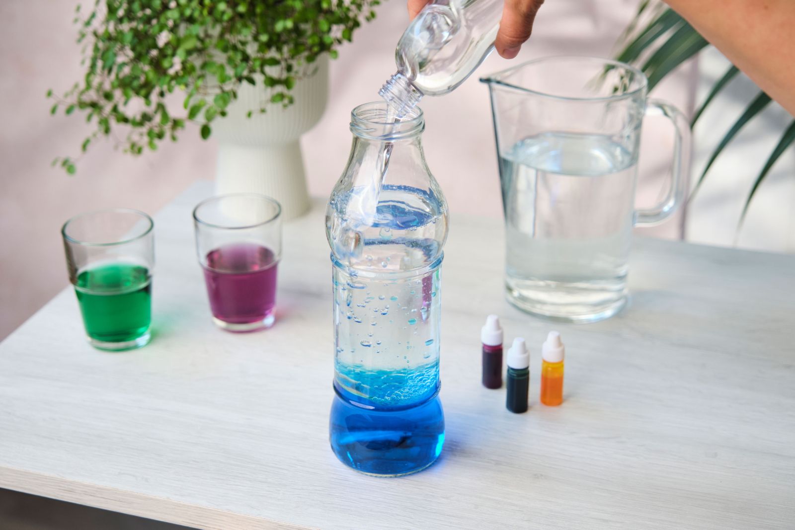 Pouring oil into a bottle over blue coloured water