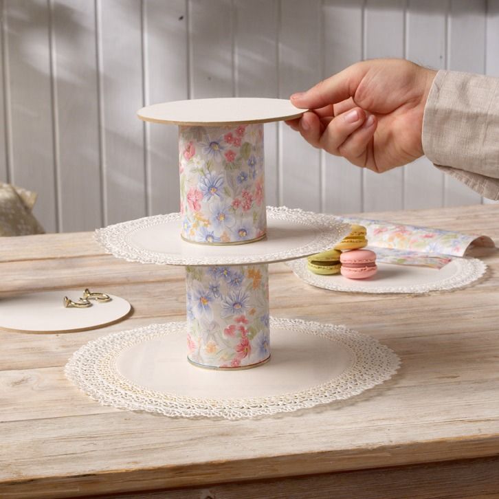 Hand stacking floral fabric-covered cans into a tiered sweets tray