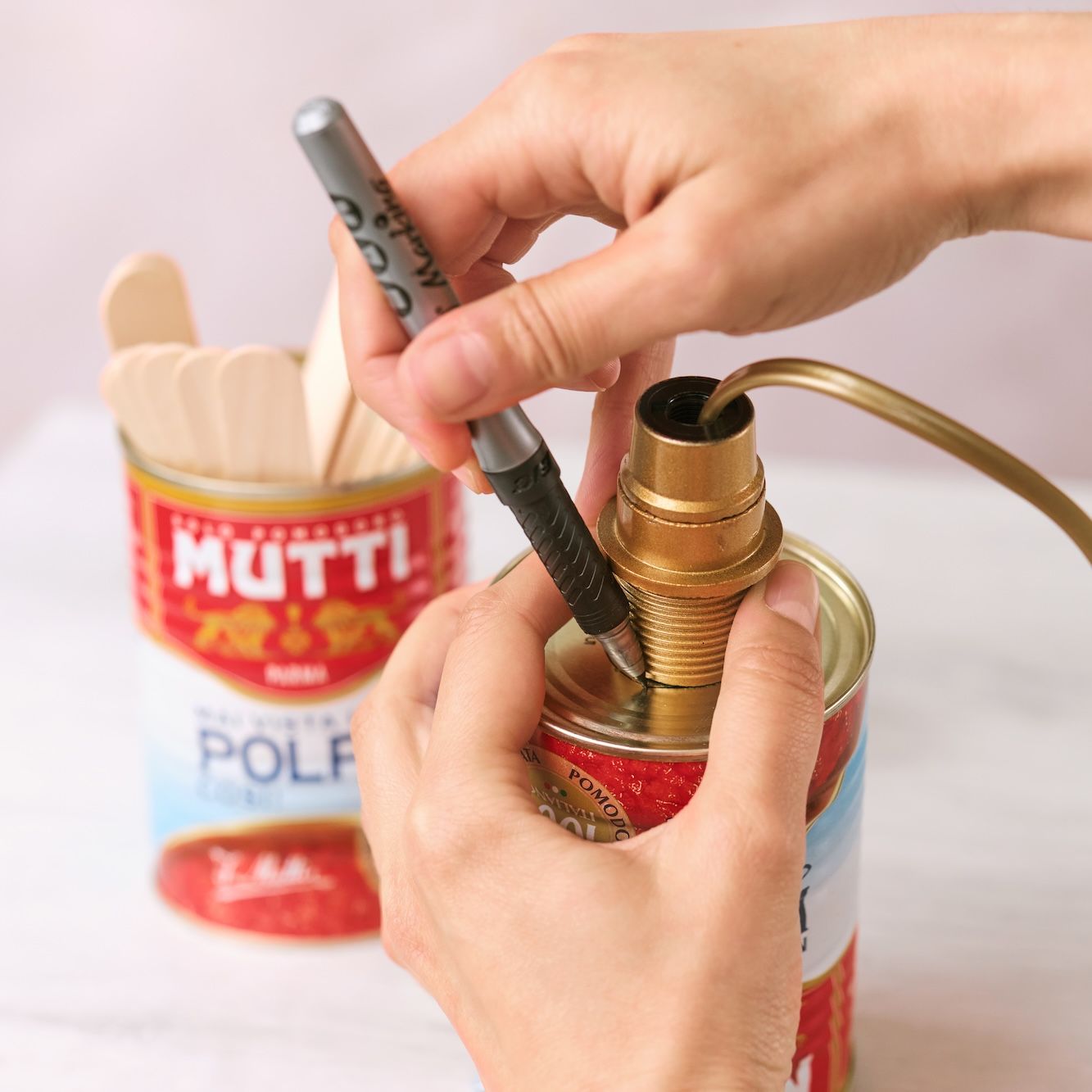 Hands fitting a lamp holder into a Mutti Polpa can