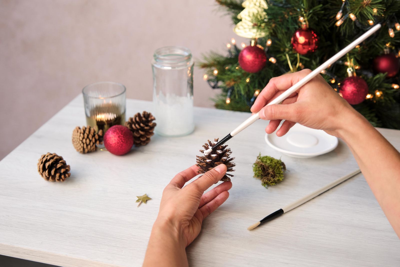 Brushing white paint onto a pinecone for a snowy look