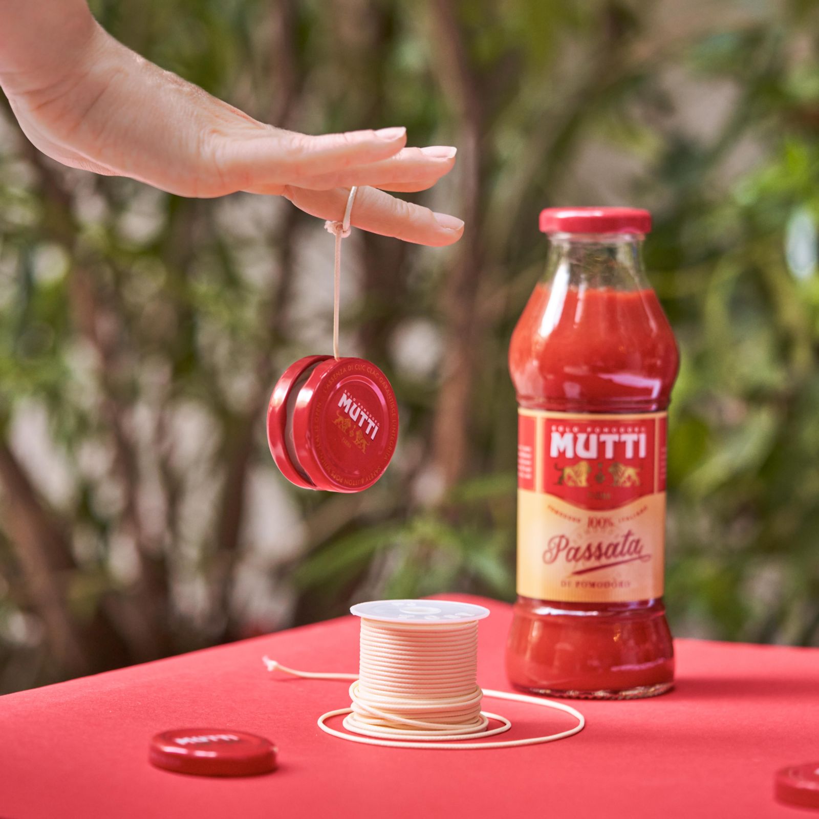 Hand spinning a red yo-yo made from Mutti bottle caps outdoors