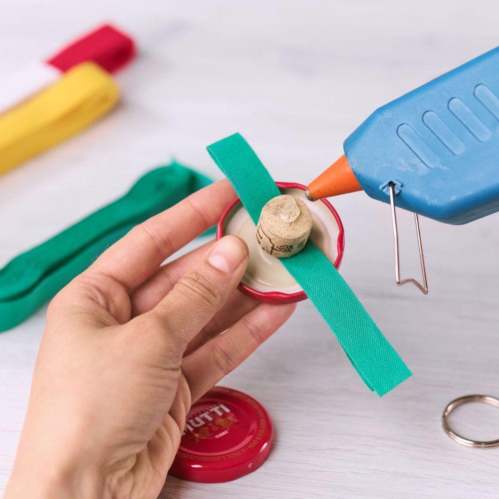 Applying hot glue to a cork inside a Mutti bottle cap