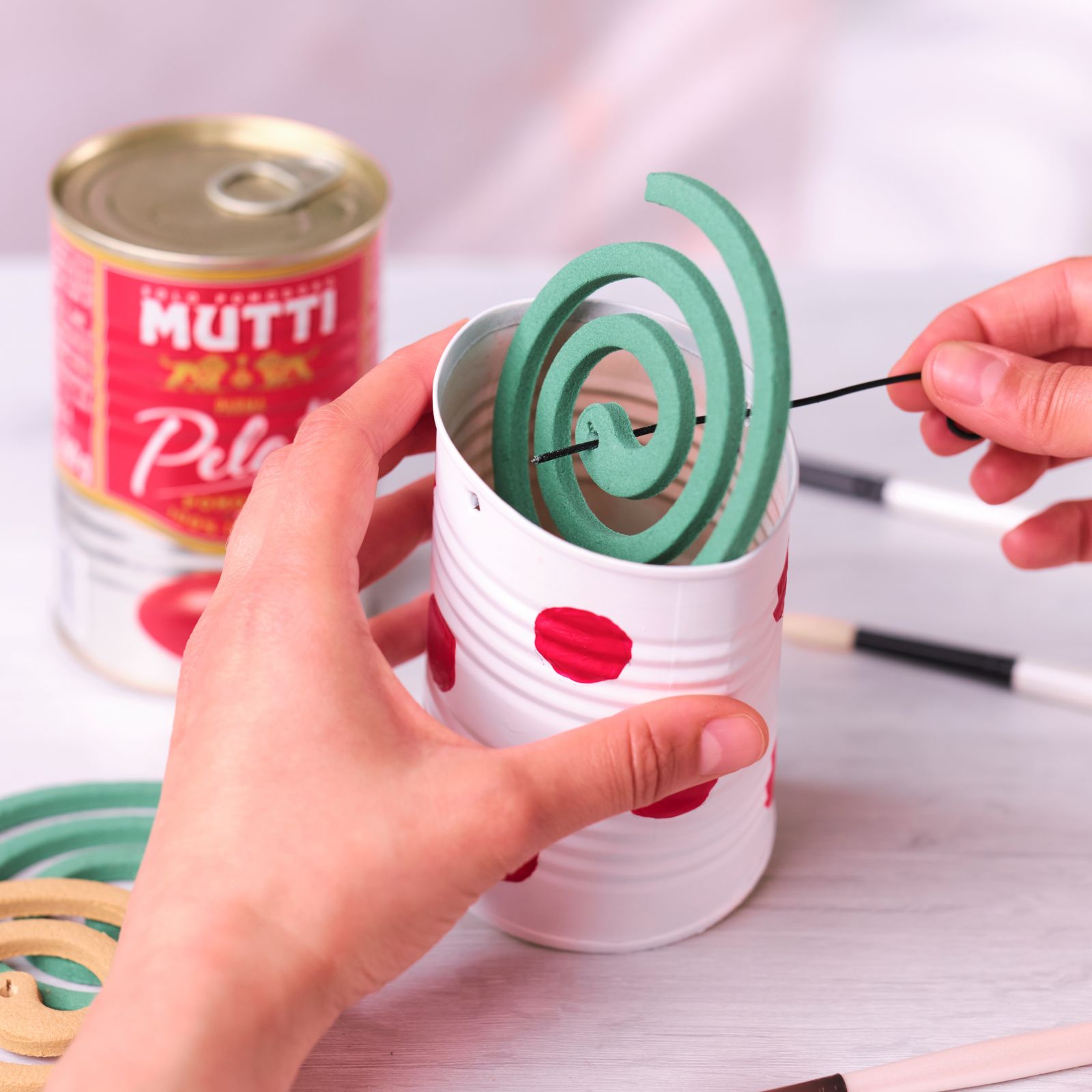 Placing a green mosquito coil into a red-dotted tin can