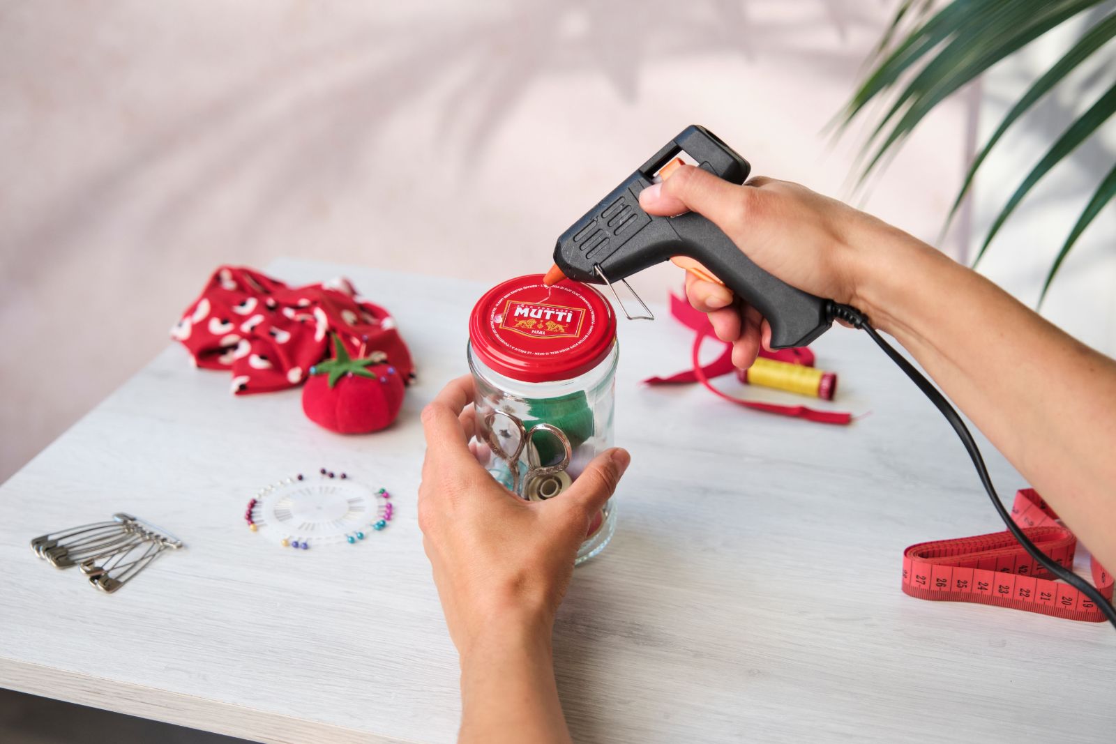 Using a hot glue gun to attach a fabric dome to a jar lid