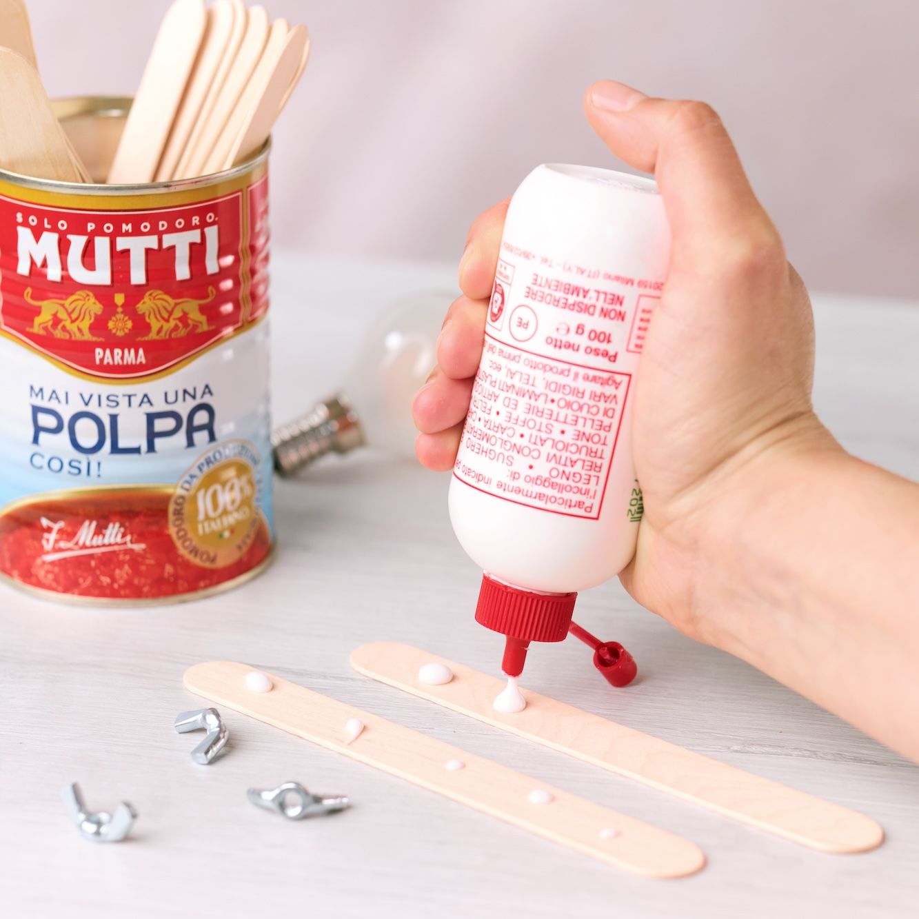 Applying drops of glue to two wooden craft sticks