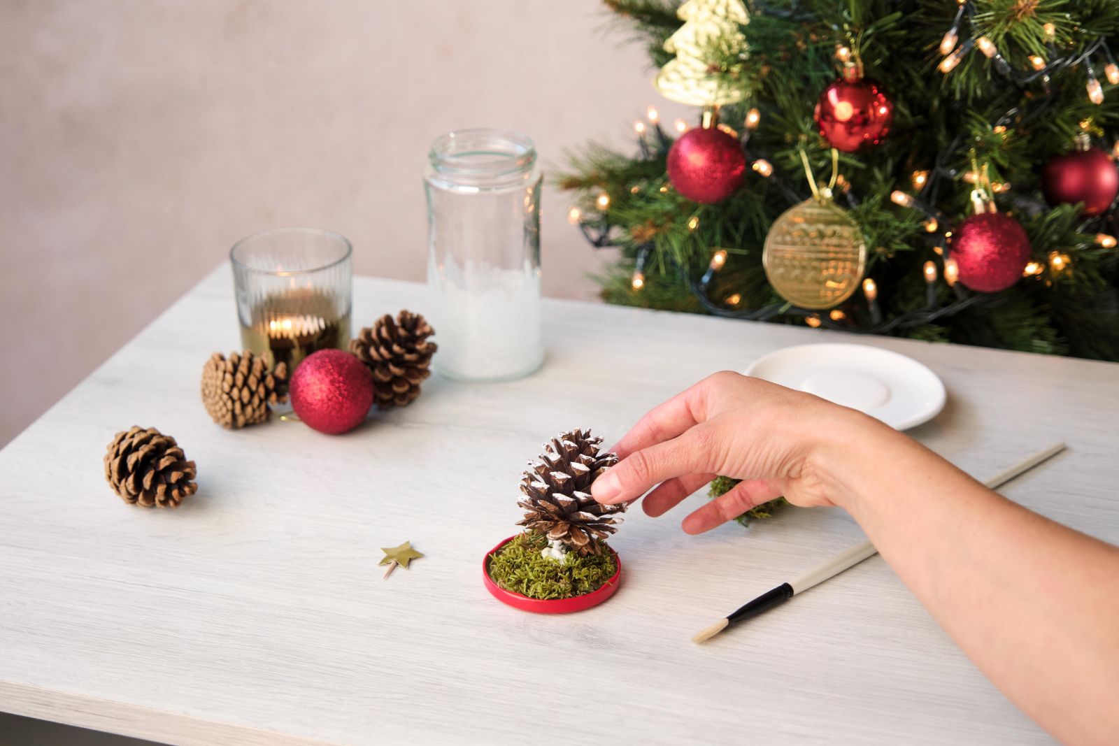 Gluing a pinecone onto a moss-covered red base