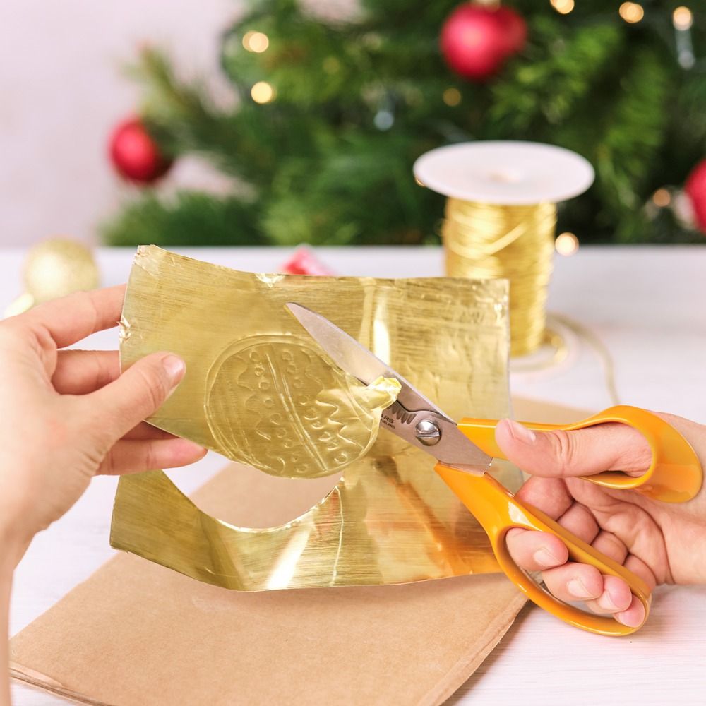Cutting out a gold bauble ornament shape with scissors