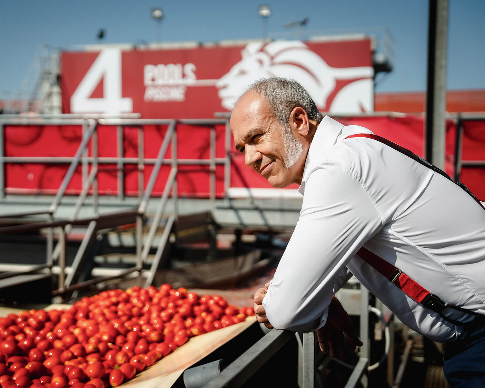 Man in a white shirt inspecting fresh tomatoes on a processing line at a Mutti facility